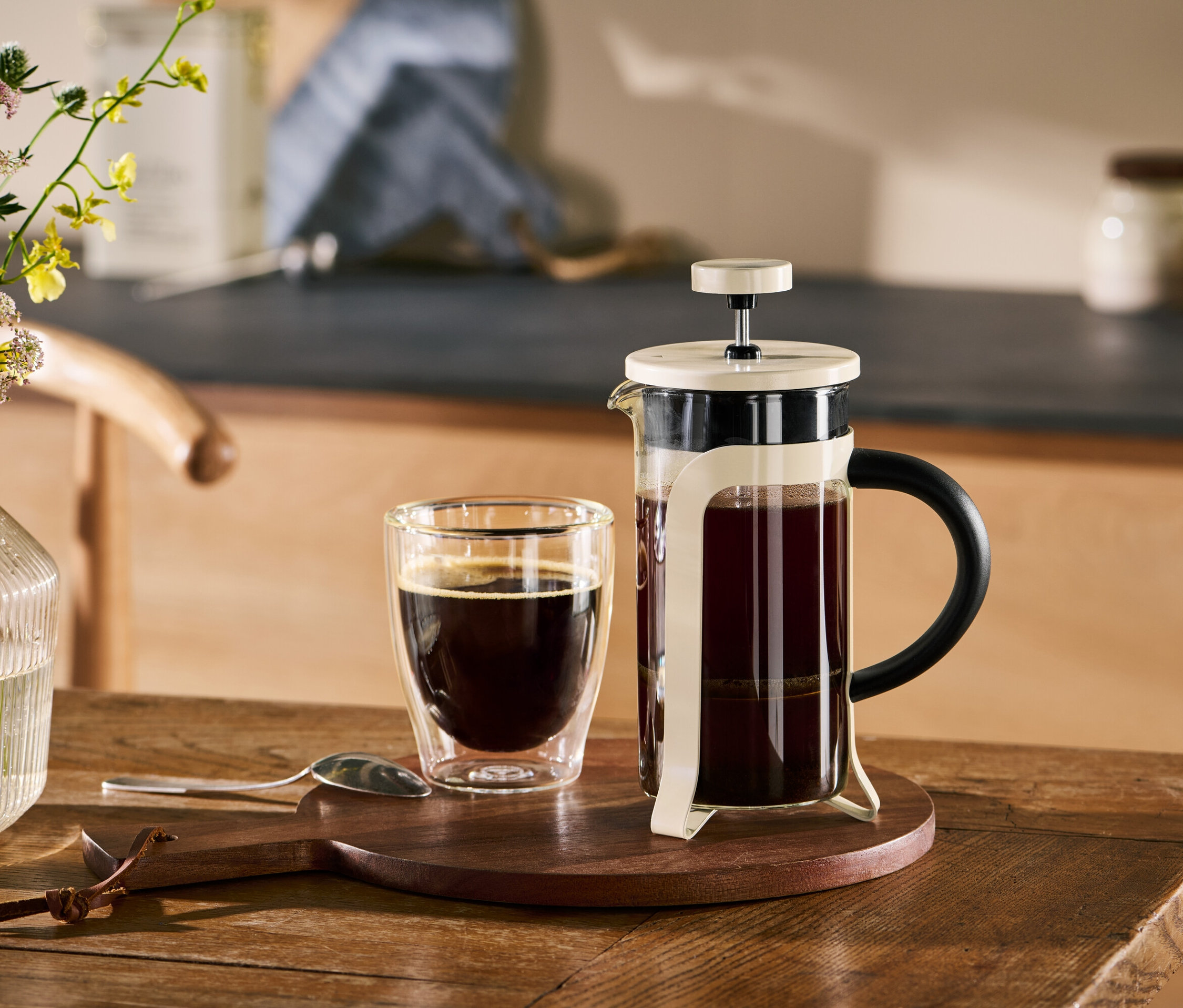 Une cafetière à piston beige 300 ml et une tasse de café sur une table en bois.
