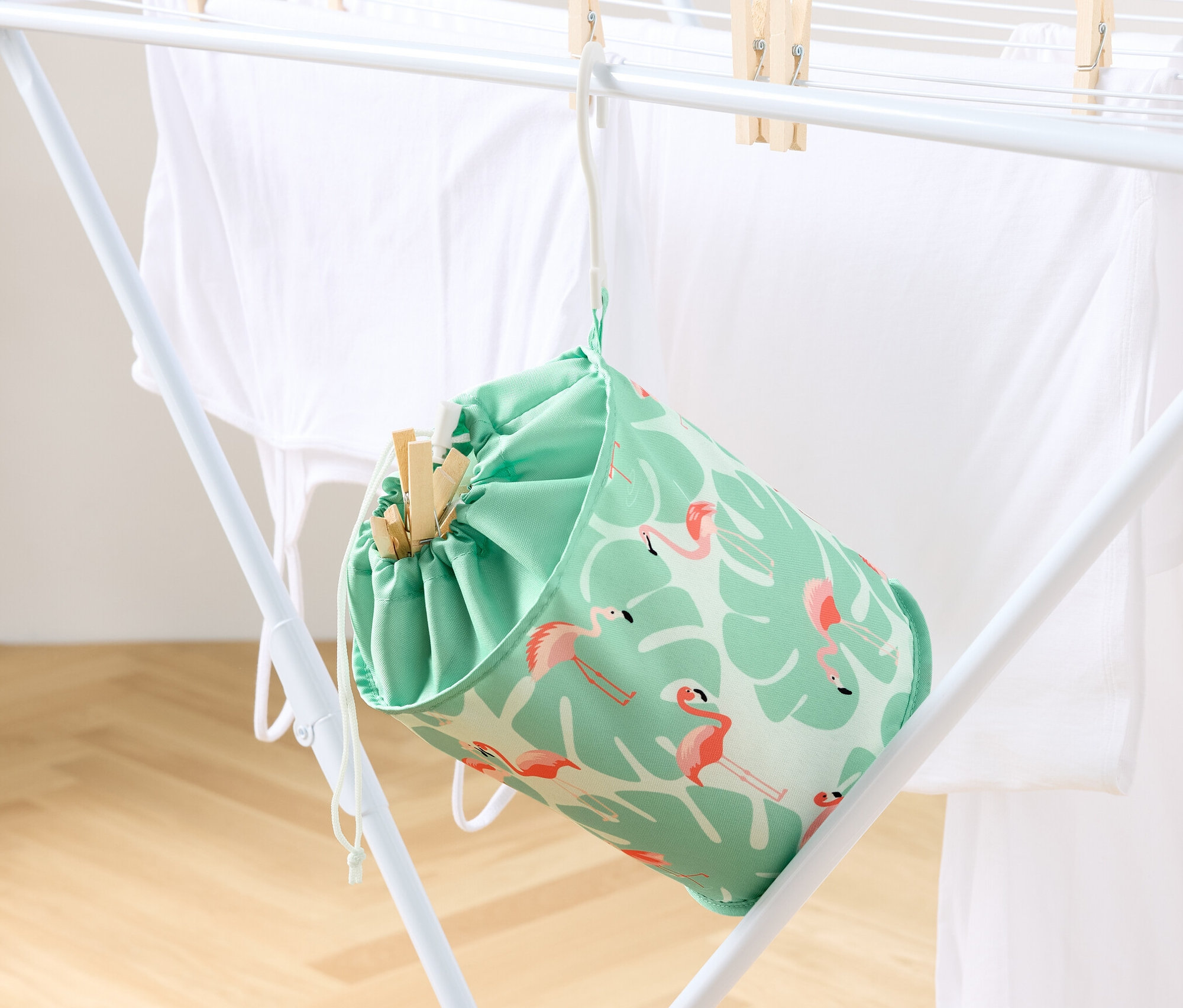 Un sac à pinces à linge est suspendu à un séchoir avec du linge.