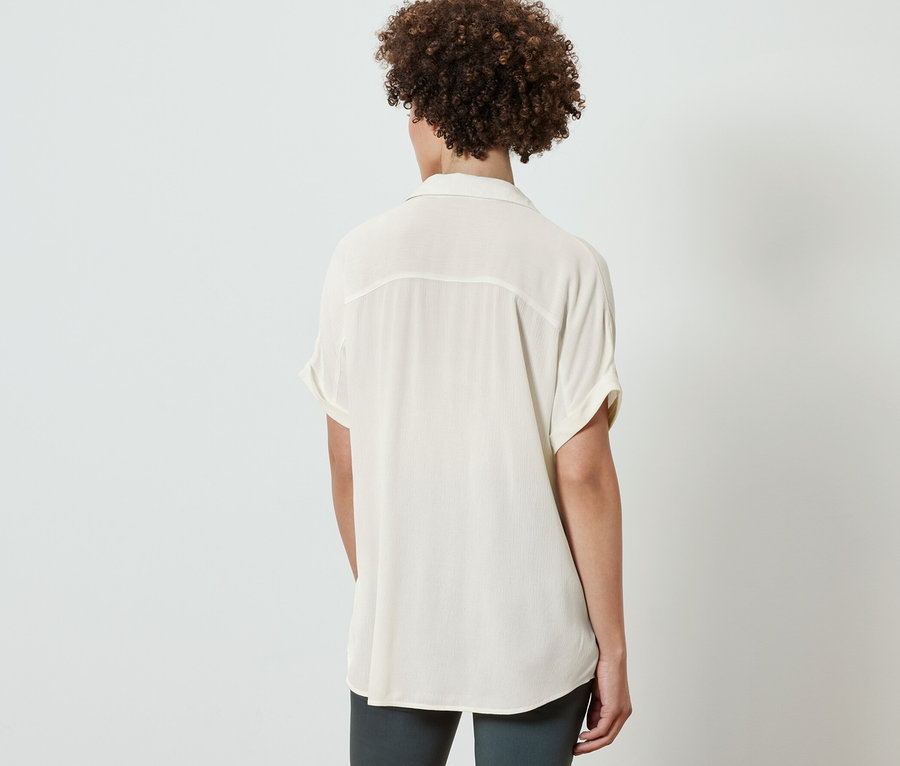 Vue arrière d'une femme portant une blouse crème.