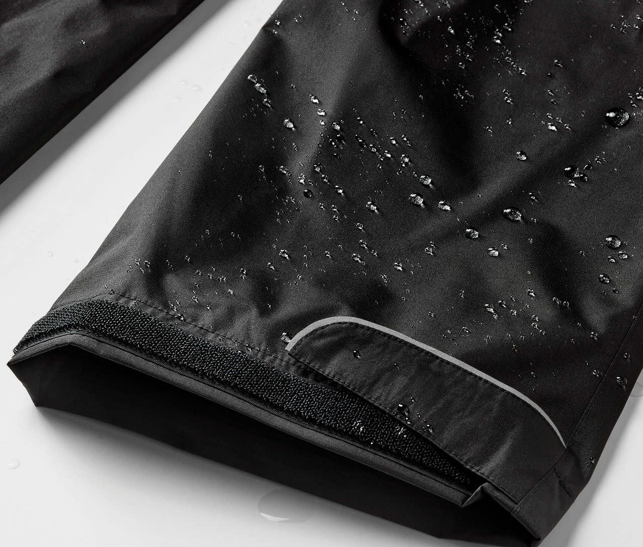 Gros plan sur un pantalon de pluie noir avec des gouttes d'eau.