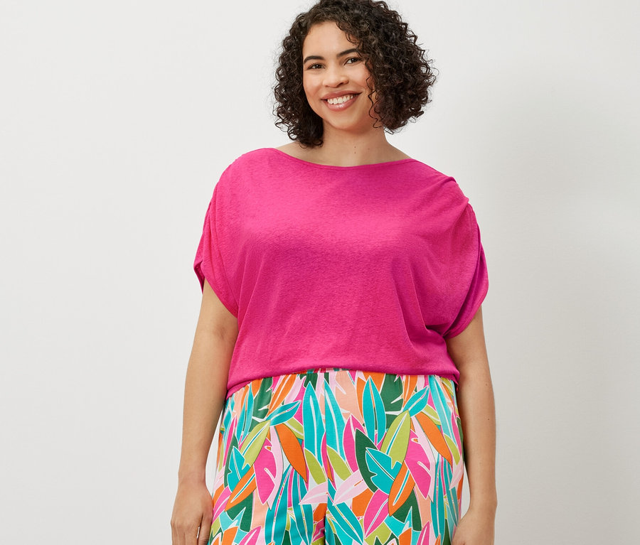 Une femme portant un pantalon palazzo imprimé multicolore et un t-shirt en lin mélangé.