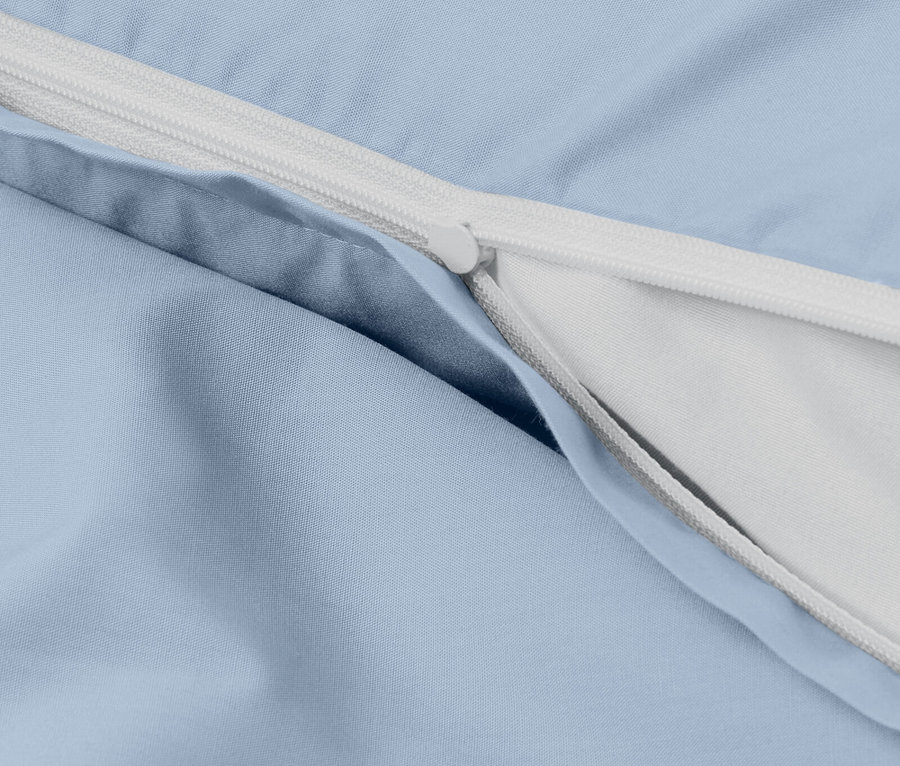 Détail d'une housse de couette bleu clair avec une fermeture éclair blanche.