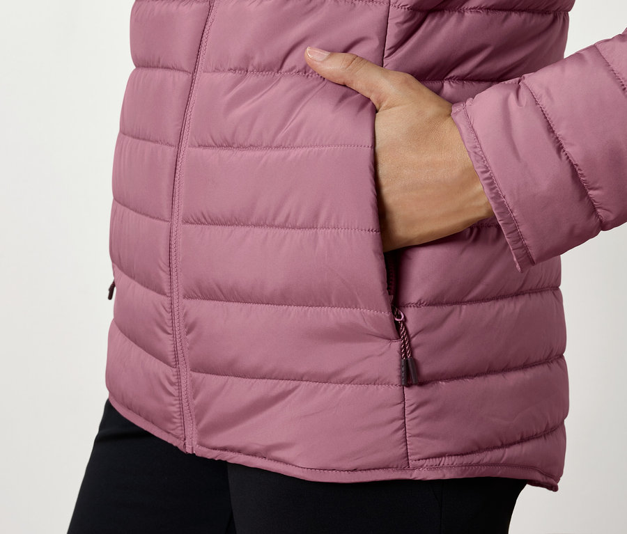 Gros plan sur une doudoune matelassée pour femme avec une main dans la poche.