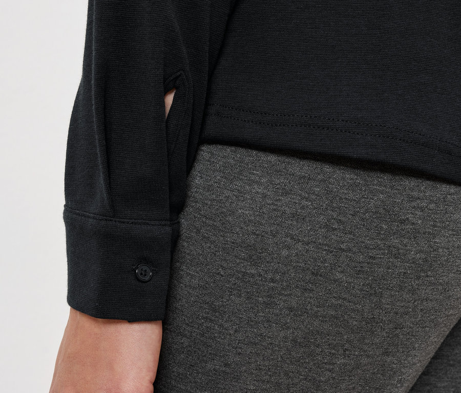 Gros plan d'une tenue pour femme comprenant un chemisier noir et un legging gris.