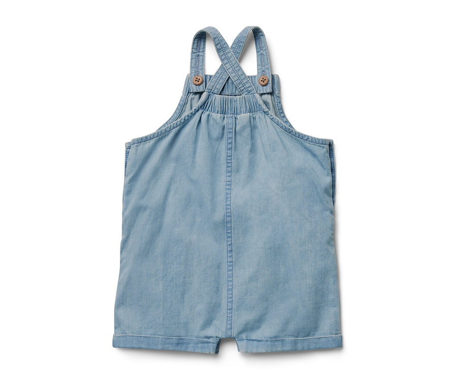 Une salopette en chambray pour enfant sur un fond blanc.