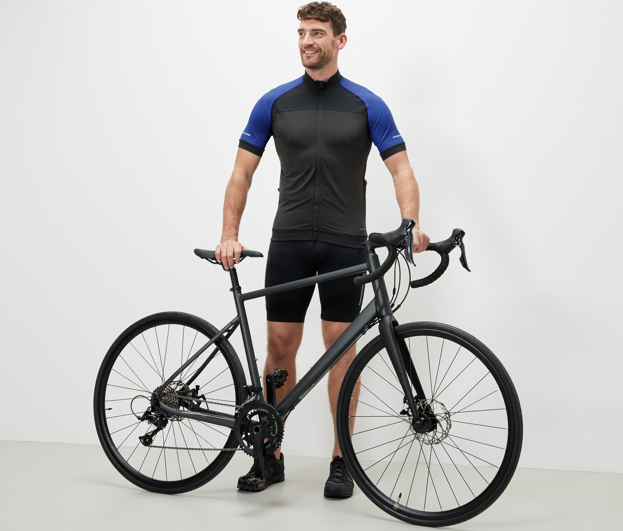 Un homme se tient à côté d'un vélo et porte un maillot de cyclisme bleu.