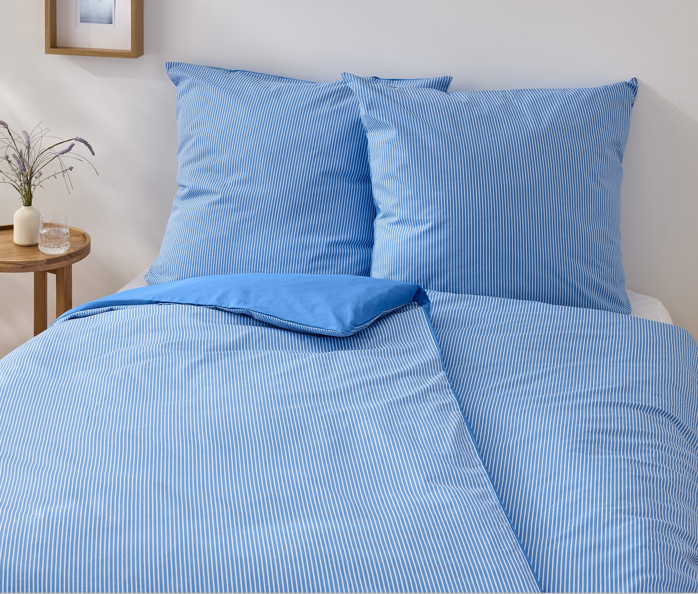 Un ensemble de literie en renforcé bleu et blanc de taille standard est disposé sur un lit.