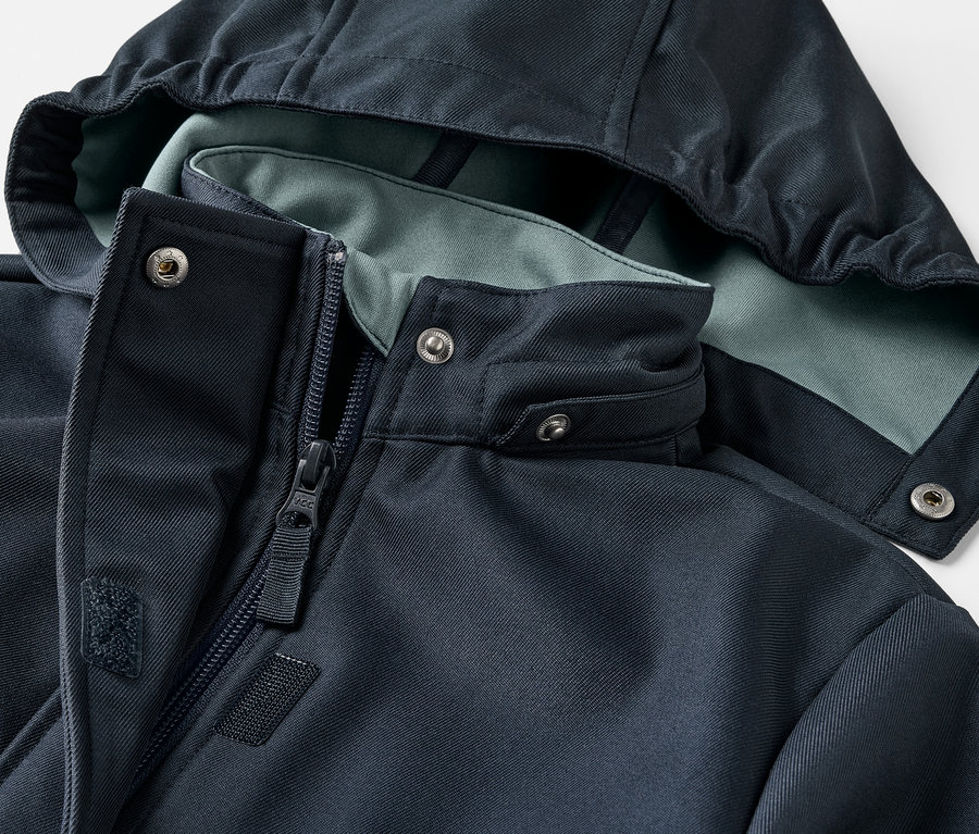 Détail d'un manteau en softshell pour enfant avec capuche et fermeture éclair.