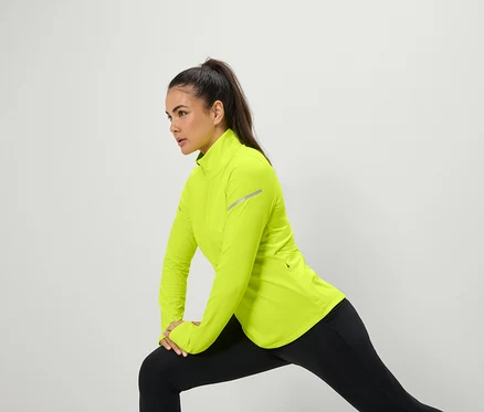 Femme s'étirant en veste jaune néon et leggings noirs.
