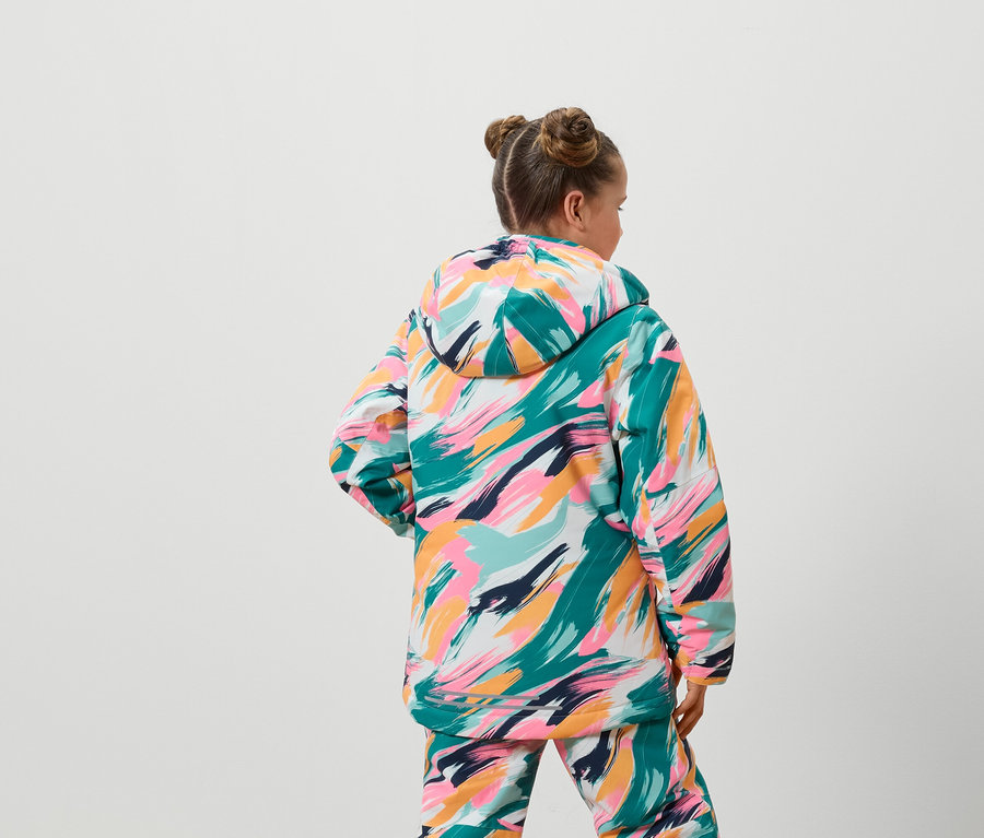 De dos, une fille portant une veste et un pantalon colorés.