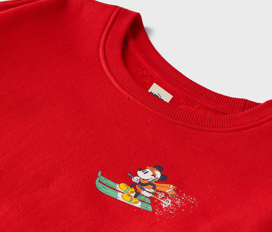 Pull rouge avec Mickey Mouse faisant du ski.