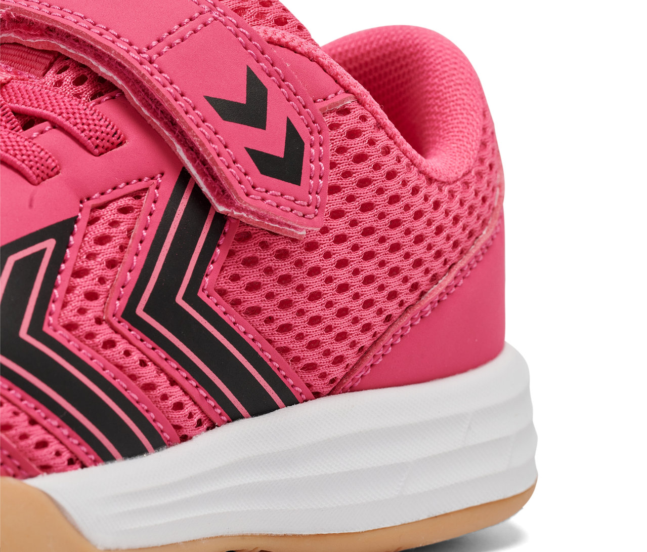 Gros plan d'une chaussure rose HUMMEL Multiplay Flex VC JR avec des rayures noires et une semelle blanche.