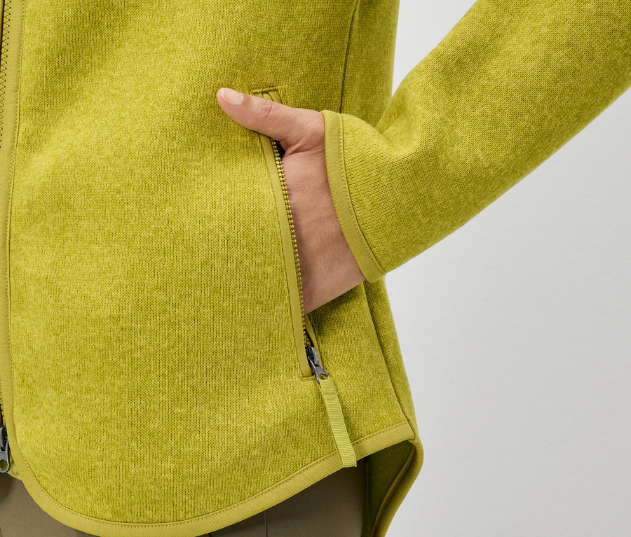 Une main dans la poche d'une veste en polaire jaune.