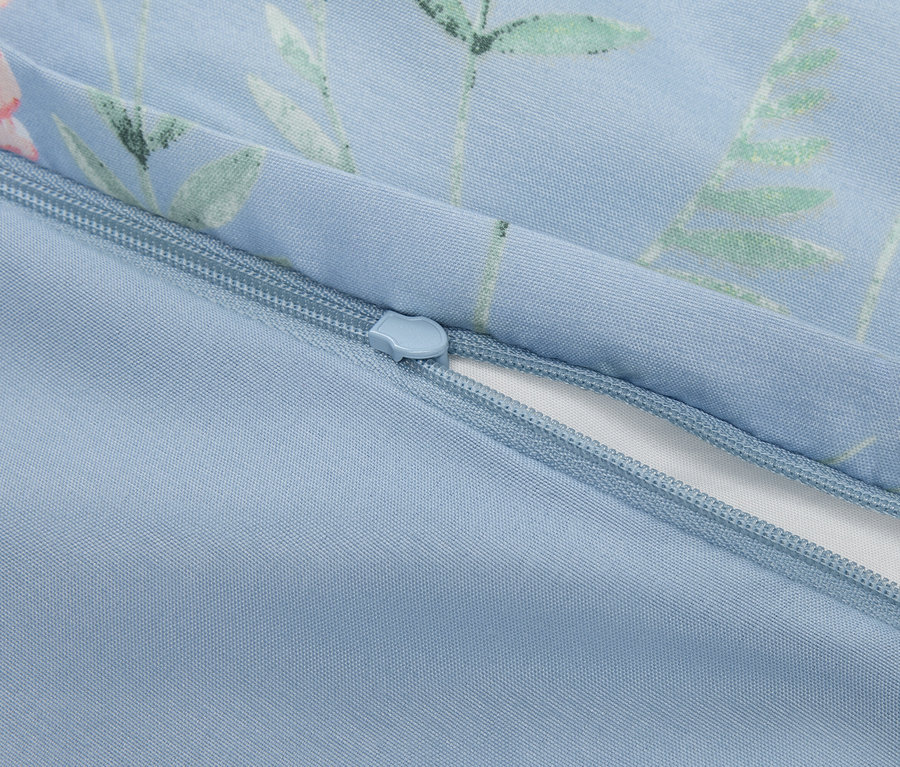 Gros plan sur une fermeture éclair partiellement ouverte sur une taie d'oreiller bleu clair à motifs floraux.