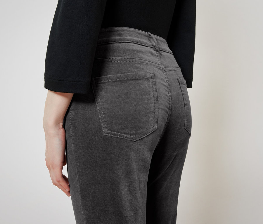 Vue arrière d'une femme portant un haut noir et un pantalon de velours côtelé gris.