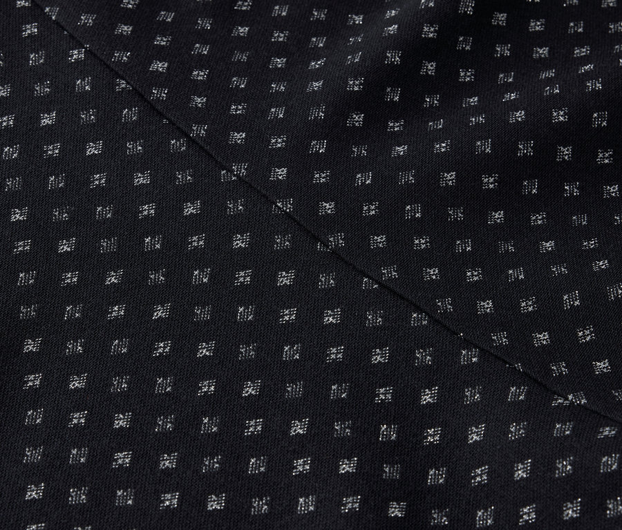 Gros plan d'un tissu noir avec un motif régulier de petits carrés blancs et une couture diagonale.