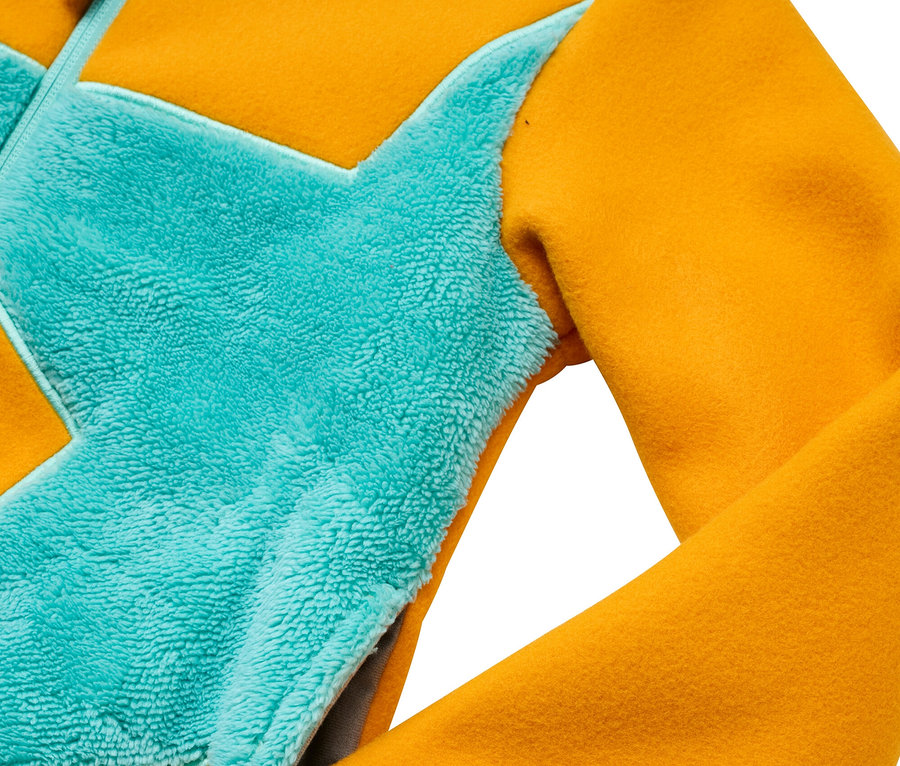 Détail d'une veste jaune et turquoise avec une poche.