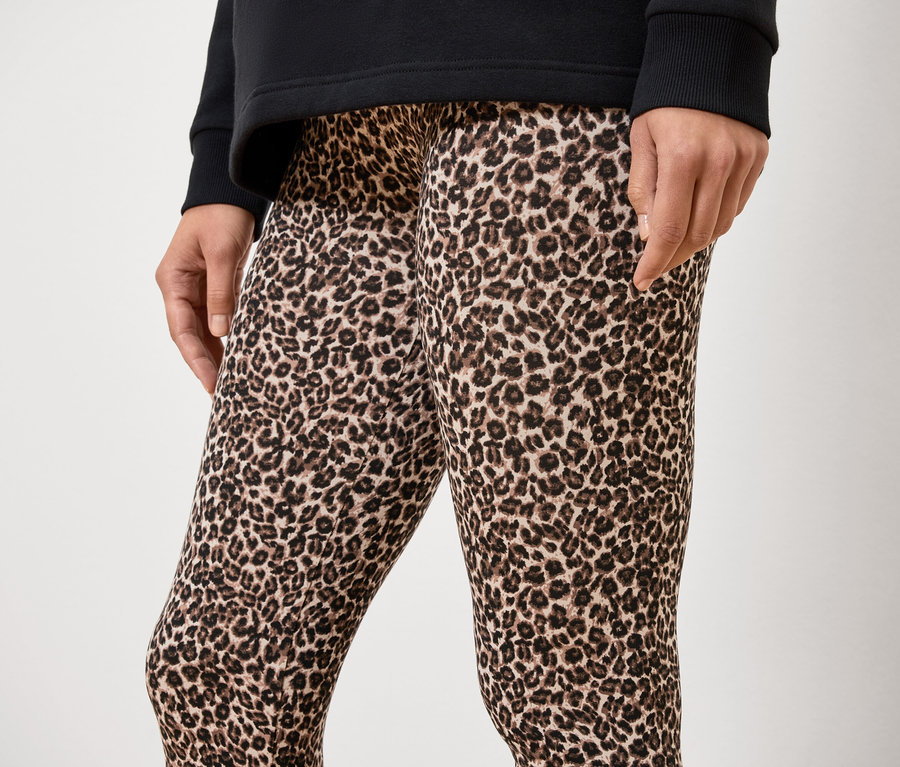 Une personne inconnue porte un haut noir et un legging à imprimé animal.