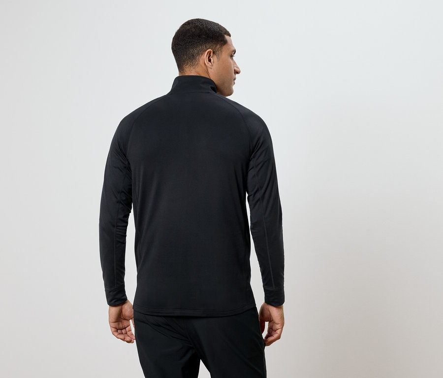 Un homme portant un t-shirt noir à manches longues et un pantalon, vu de dos.