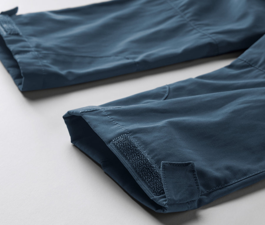 Gros plan sur le bas des jambes d'un pantalon fonctionnel bleu pour tout-petit avec des bandes velcro.