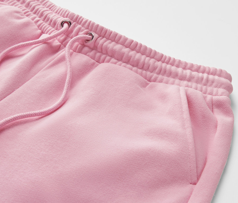 Détail d'un pantalon de jogging rose avec taille élastique et cordon de serrage.