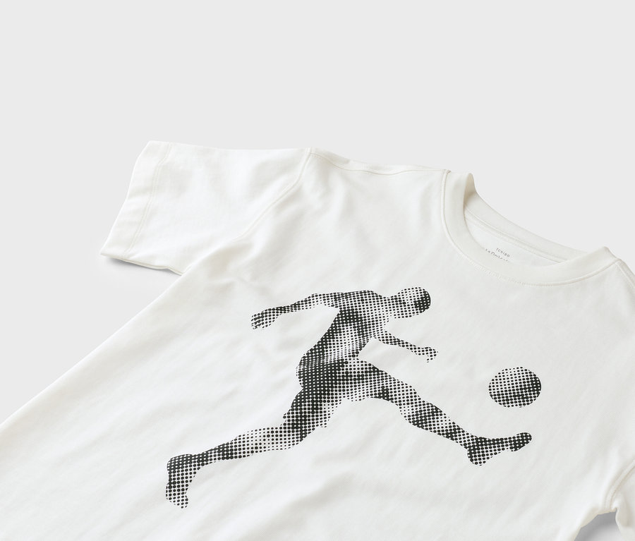 Un t-shirt blanc avec l'imprimé d'un joueur de football donnant un coup de pied dans un ballon.
