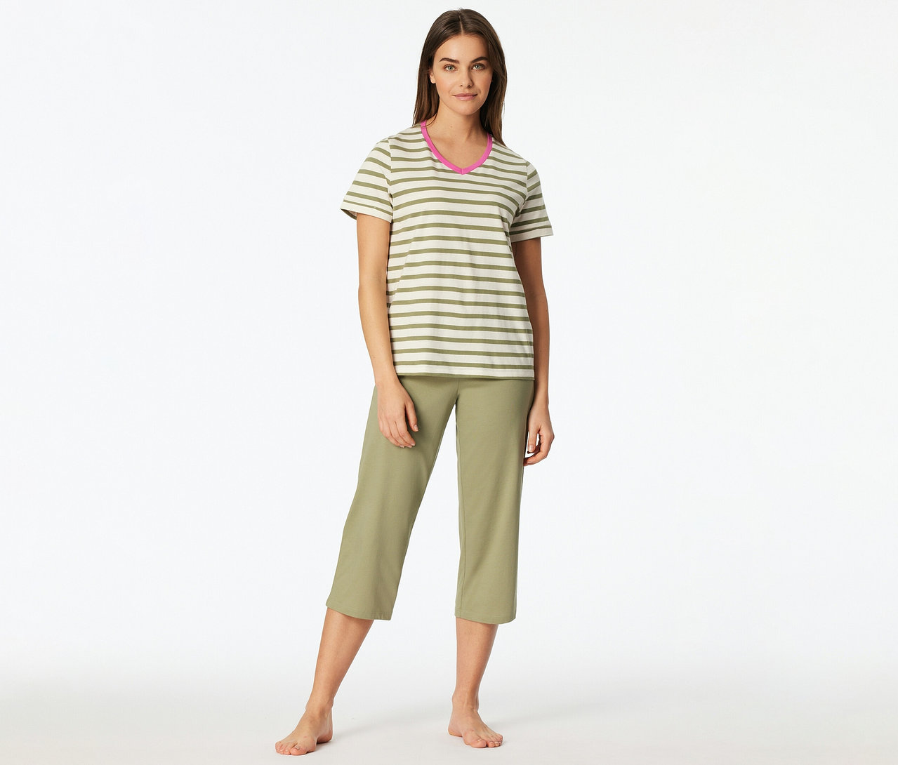 Une femme pieds nus porte un set de pyjama 3/4 SCHIESSER. Le haut est rayé vert et blanc avec un col en V rose, le pantalon est un capri vert.