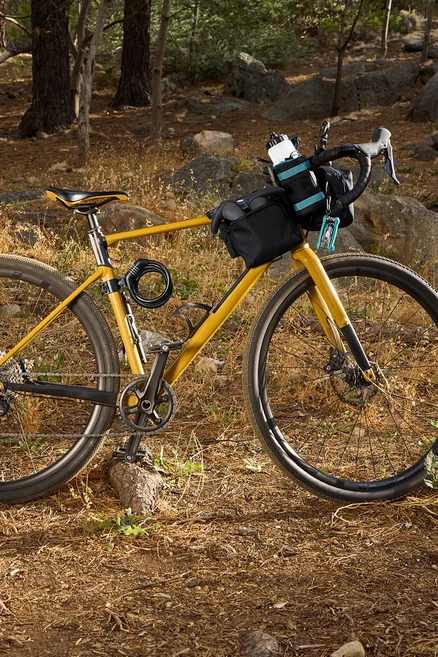 Vélo jaune avec sacoches noires et accessoires en forêt.