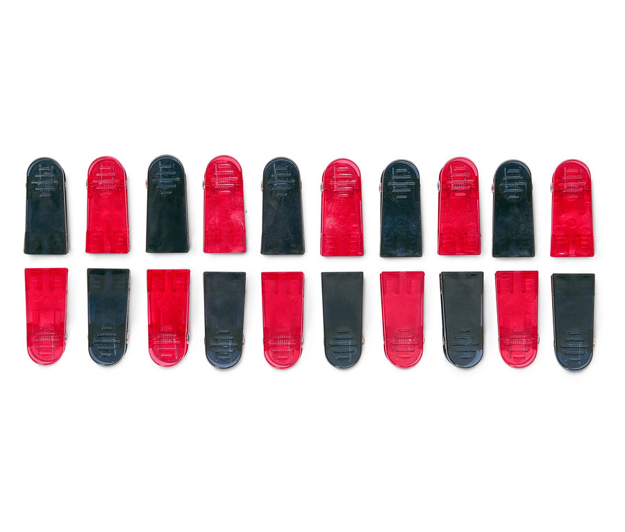 Vue de dessus de deux rangées de pinces à linge rouges et noires alternées sur fond blanc.