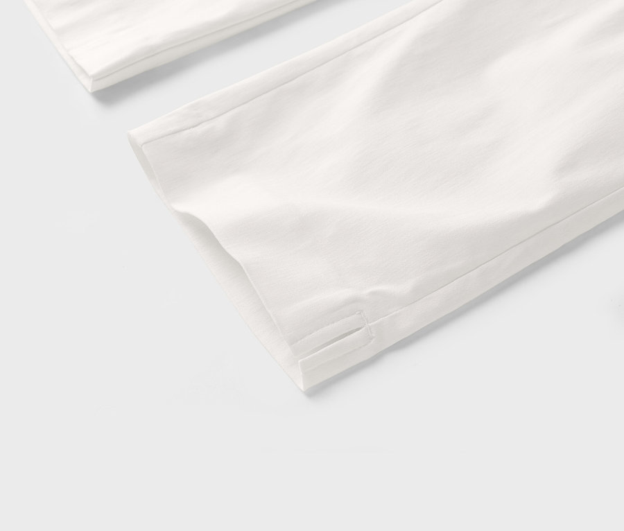 Vue détaillée de jambes de pantalon blanches sur fond blanc.