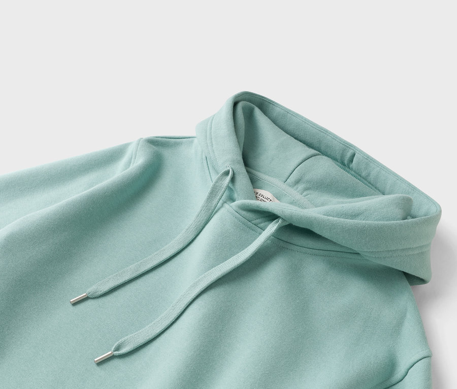 Gros plan d'un sweat à capuche vert menthe avec cordon de serrage.