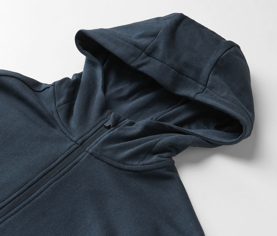 Gros plan d'un sweat-shirt à capuche bleu marine avec fermeture éclair sur fond blanc.