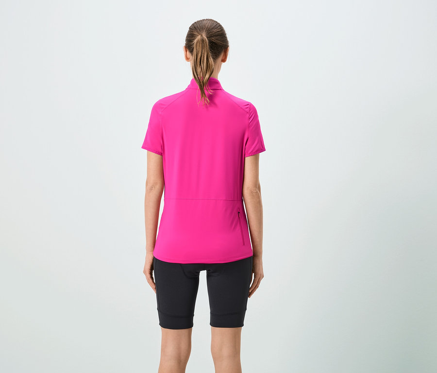 Vue arrière d'une femme avec une queue de cheval portant un maillot rose à manches courtes et un short noir.