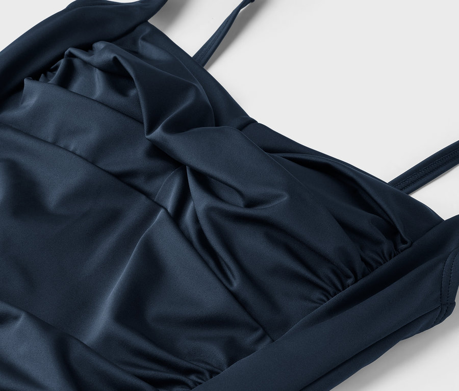 Gros plan sur un maillot de bain une pièce bleu marine pour femme avec des bretelles et des fronces au niveau de la poitrine.