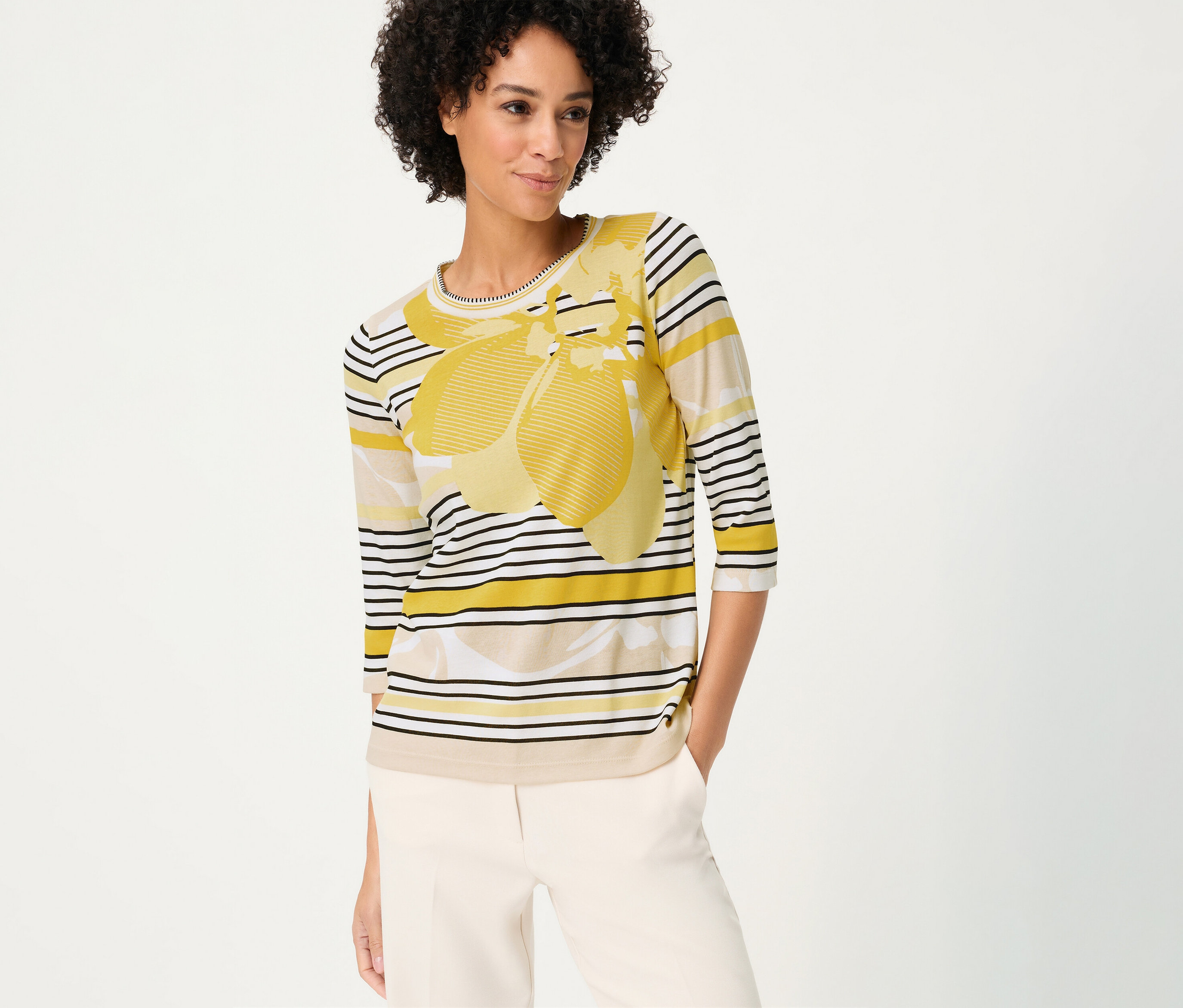 Femme portant un pantalon beige et un T-shirt 3/4 Olsen à rayures avec motif jaune.