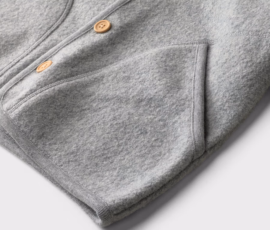Gros plan sur une veste gris clair avec deux boutons et une poche plaquée.