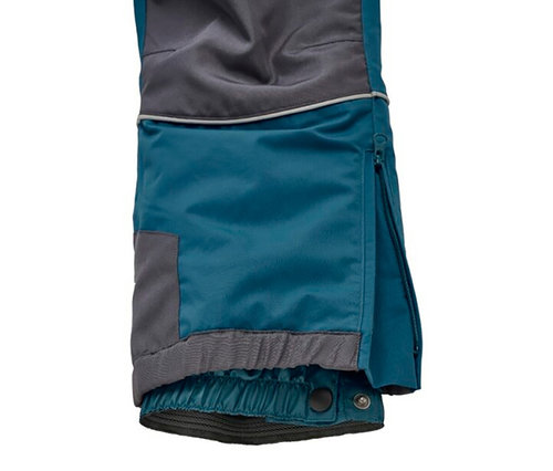 Jambe de pantalon pétrole et grise avec bande réfléchissante et fermeture éclair latérale partiellement ouverte. L'ourlet a un revers élastique gris et une doublure intérieure à boutons-pression.