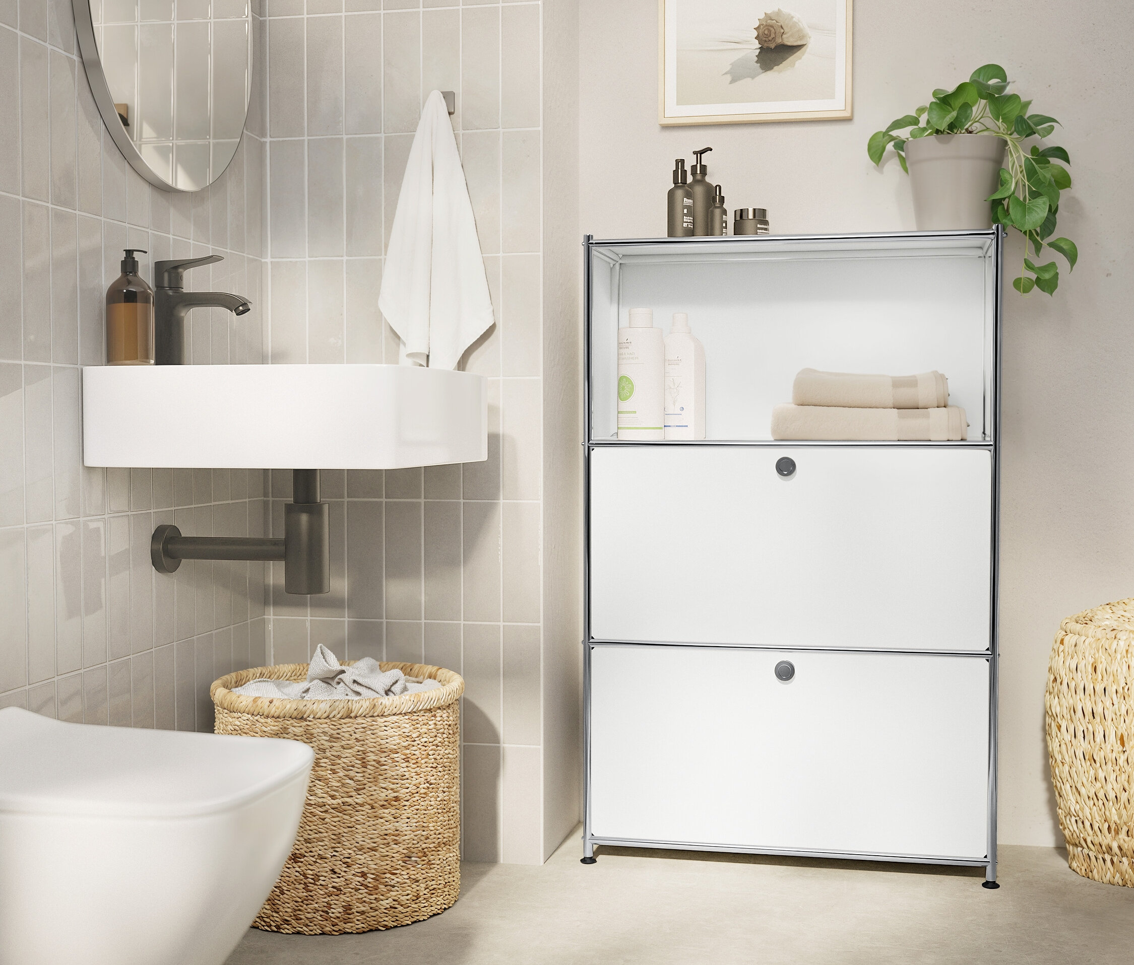Salle de bain avec lavabo blanc, miroir ovale, serviette, panier tressé et étagère blanche.
