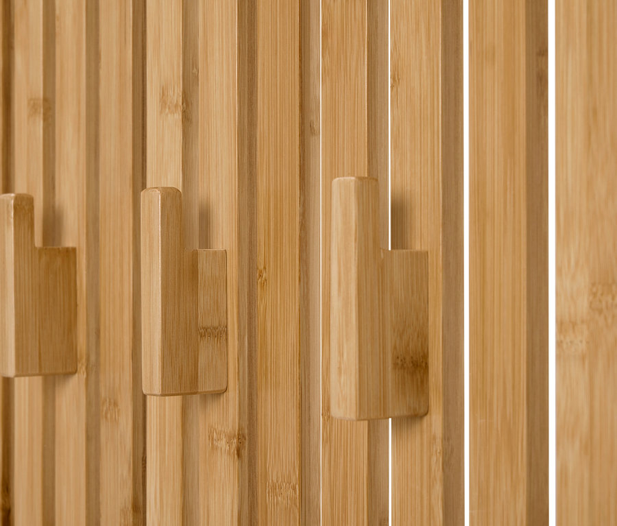 Gros plan de trois crochets à vêtements en bois sur un mur composé de panneaux de bois verticaux.