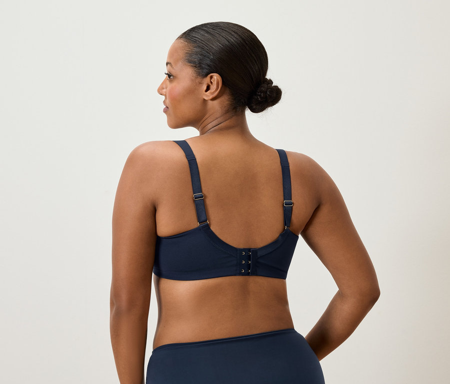 Vue arrière d'une femme avec un chignon portant un soutien-gorge et des sous-vêtements bleu marine.