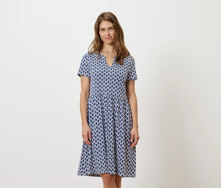 Femme debout portant une robe bleue et blanche.