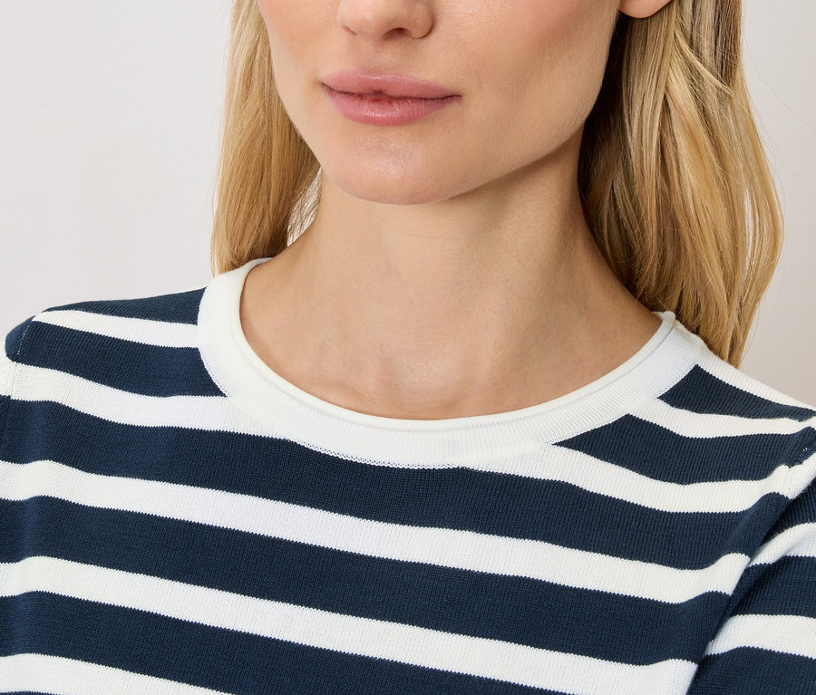 Gros plan d'une femme blonde portant un haut rayé bleu marine et blanc.