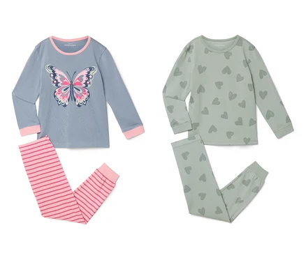 Deux ensembles de pyjamas pour enfants sont posés sur un fond blanc. Un ensemble est bleu avec un papillon et des rayures roses, l'autre est vert avec des cœurs.