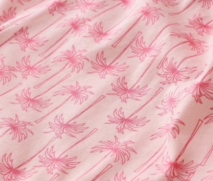 Gros plan d'un tissu rose avec un motif de palmiers.