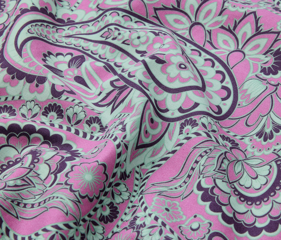 Gros plan d'un tissu avec un motif floral abstrait rose, violet et vert menthe.
