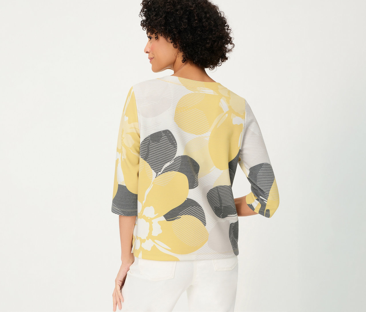 Femme de dos portant un pantalon blanc et un sweat-shirt Olsen « Ottoman » à fleurs jaunes et grises.