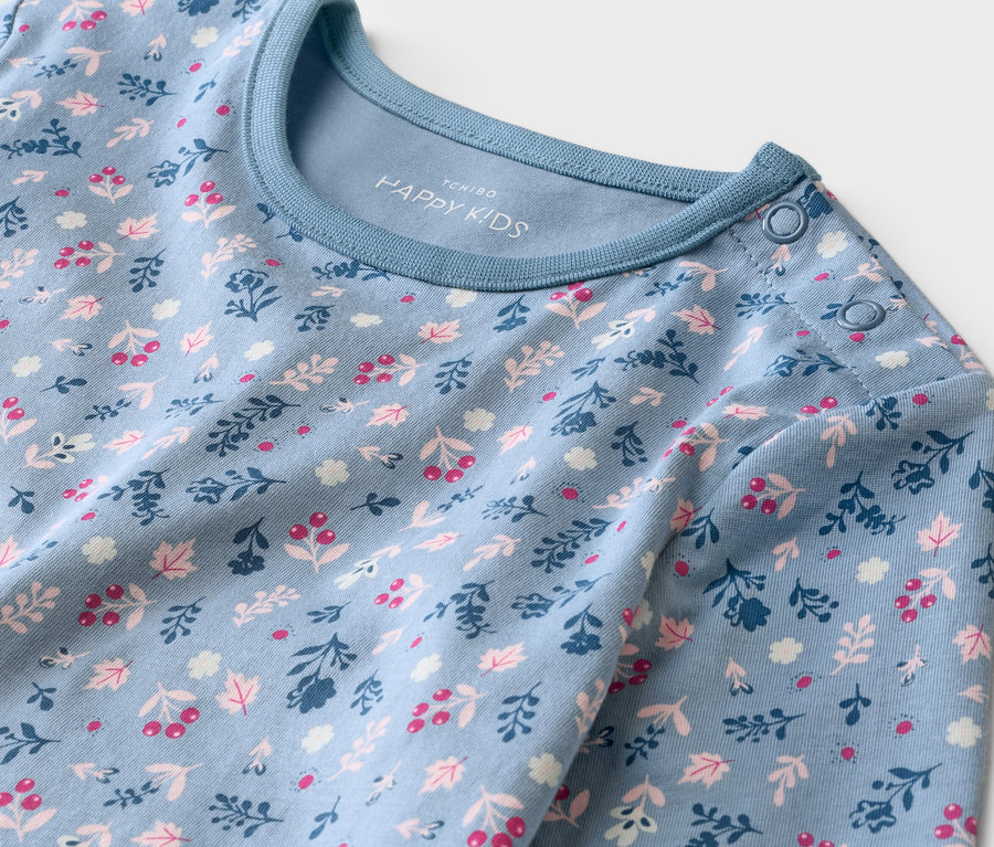 Gros plan sur un haut de bébé bleu clair à manches longues avec motif floral et boutons à l'épaule.