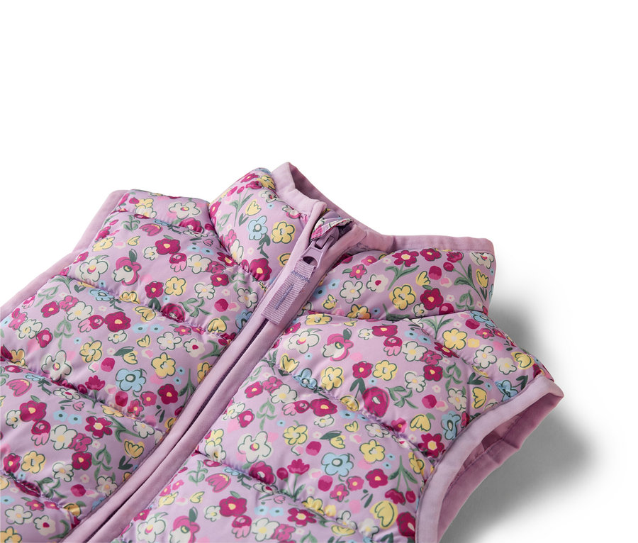 Gros plan sur un gilet matelassé lilas à motif floral avec fermeture éclair.