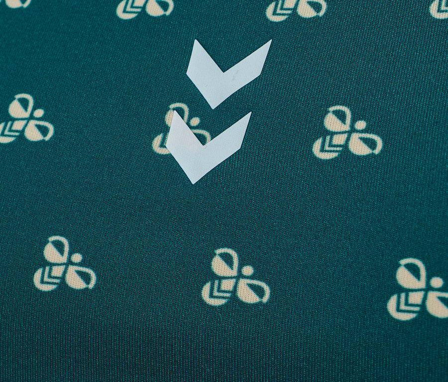 Gros plan d'un tissu vert avec un motif de logos d'abeilles couleur crème et de chevrons blancs.