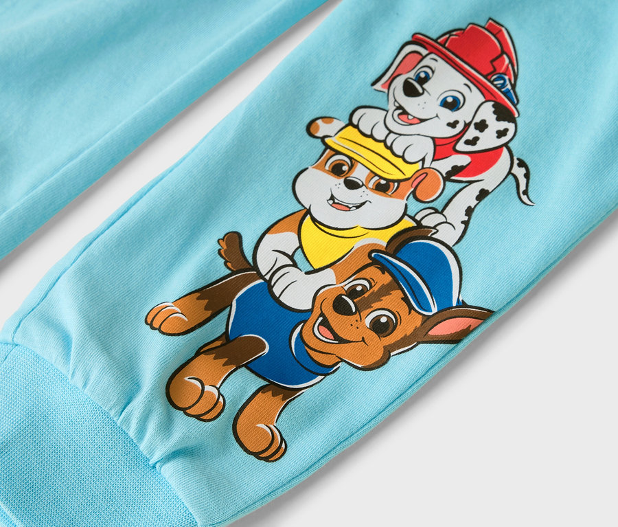 Gros plan sur une jambe de pantalon bleu clair avec les personnages de Pat' Patrouille : Marcus, Ruben et Chase.
